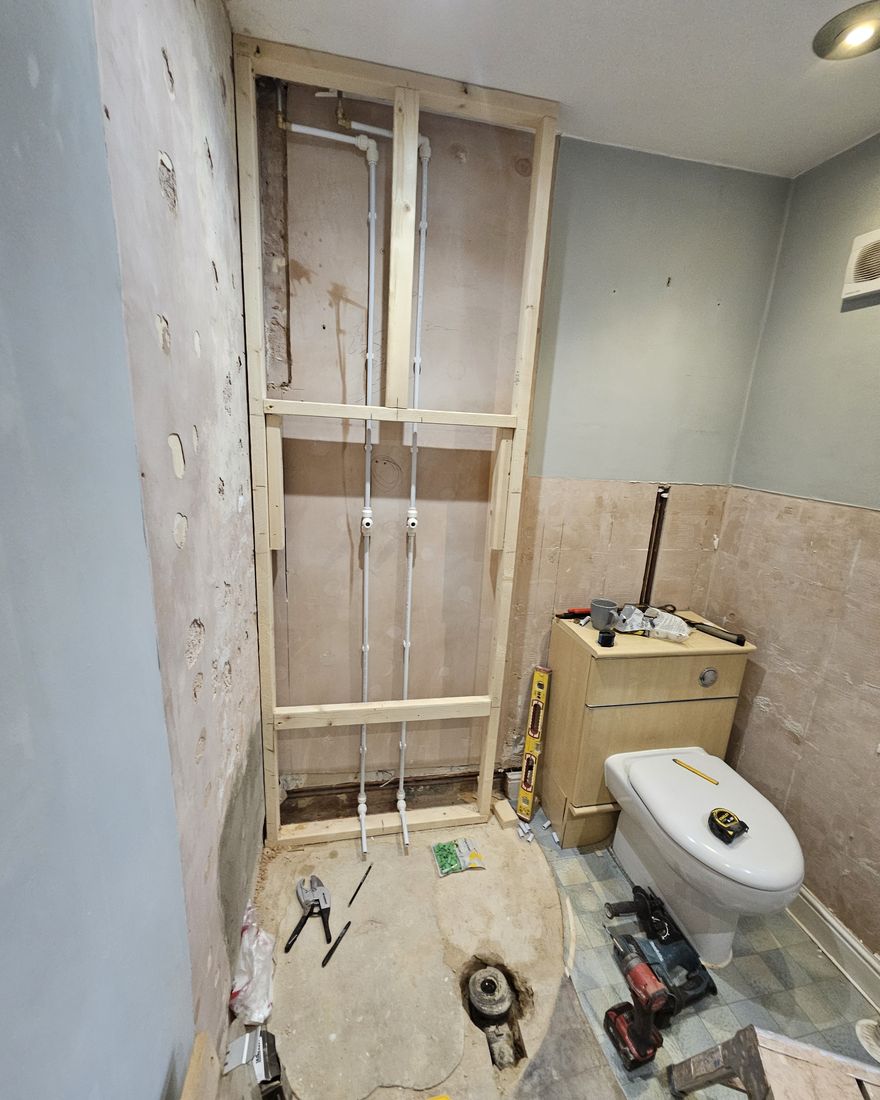 New timber stud framing and pipework where the shower was, with the toilet still in place