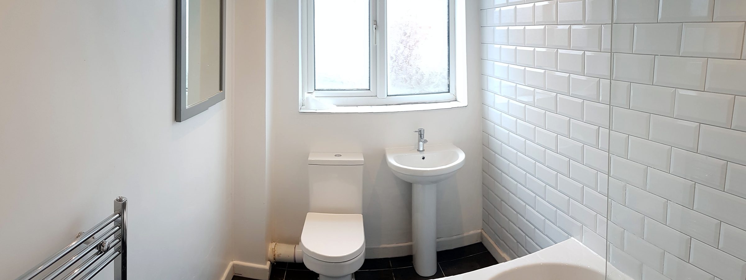 Bright finished bathroom by JonesBuild: metro-tiled wall, new bath, toilet and basin