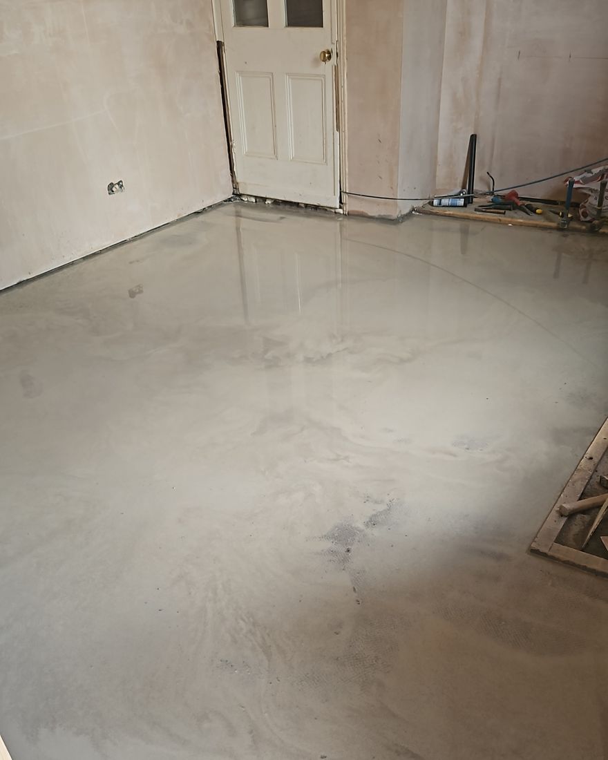 The new floor base laid and the walls plastered, with a glazed panel door at the far end