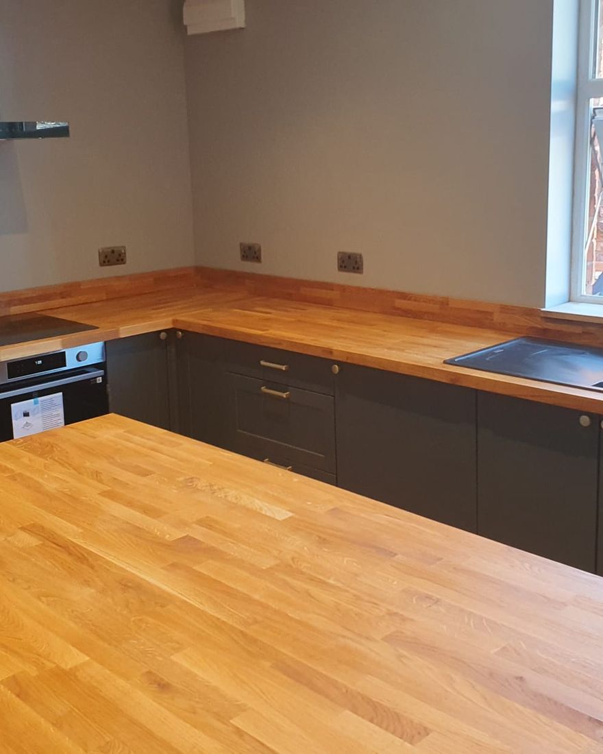 The finished island with an oak top in front of the sink run and dark units