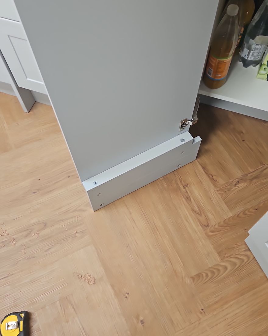 Herringbone flooring being laid up to the skirting and a tall unit