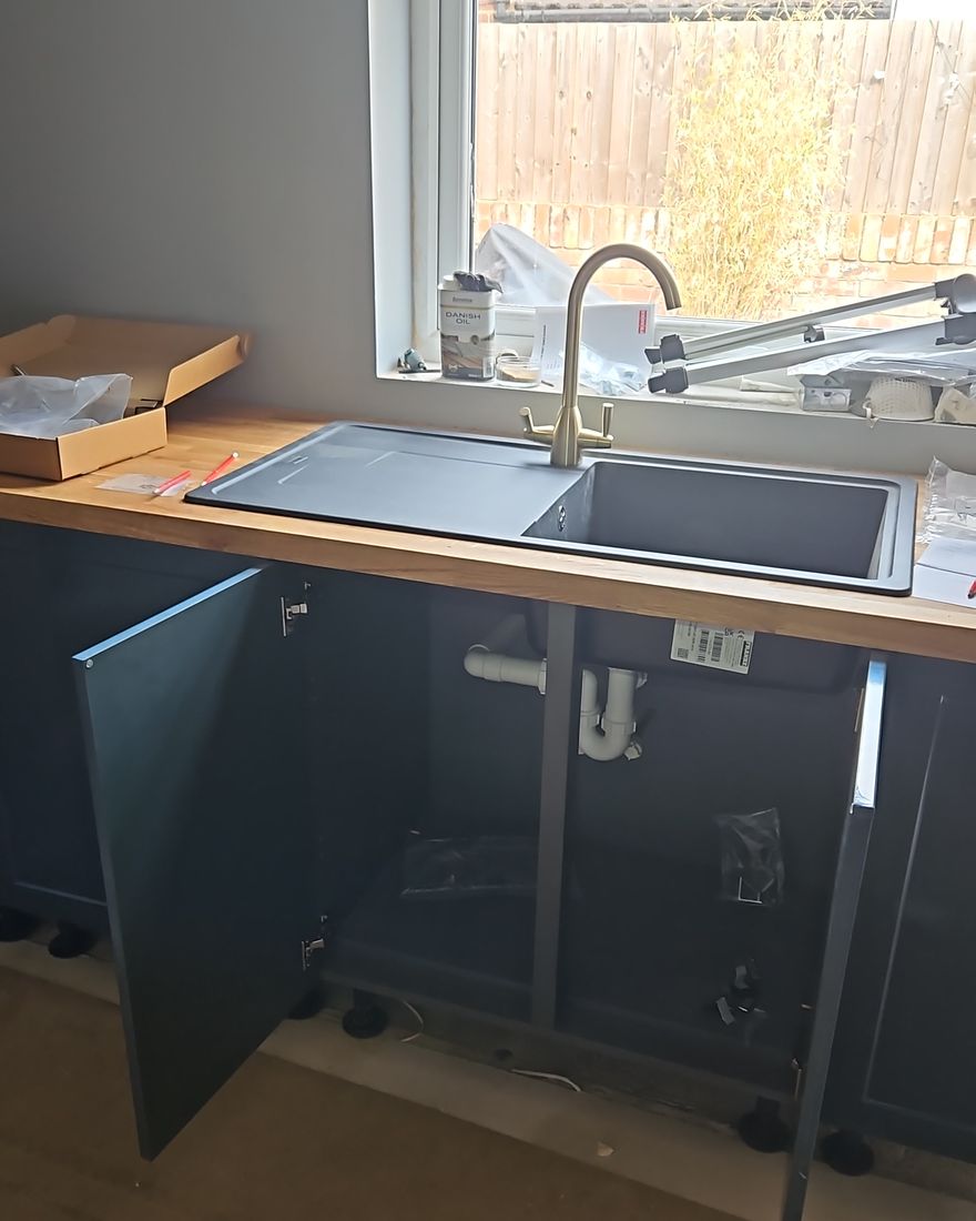 Dark blue base units with a sink set into the oak worktop under the window