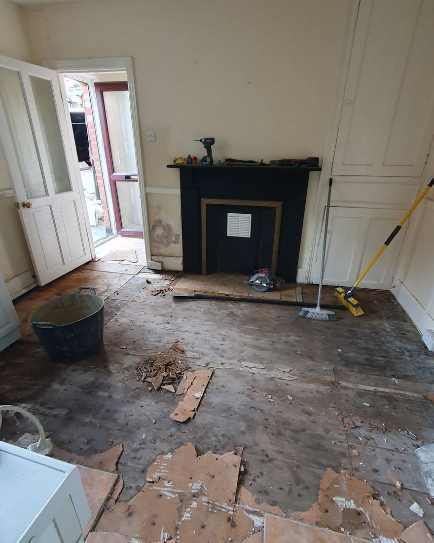 The kitchen stripped out, with the old floor coverings lifted and an old fireplace still in the chimney breast