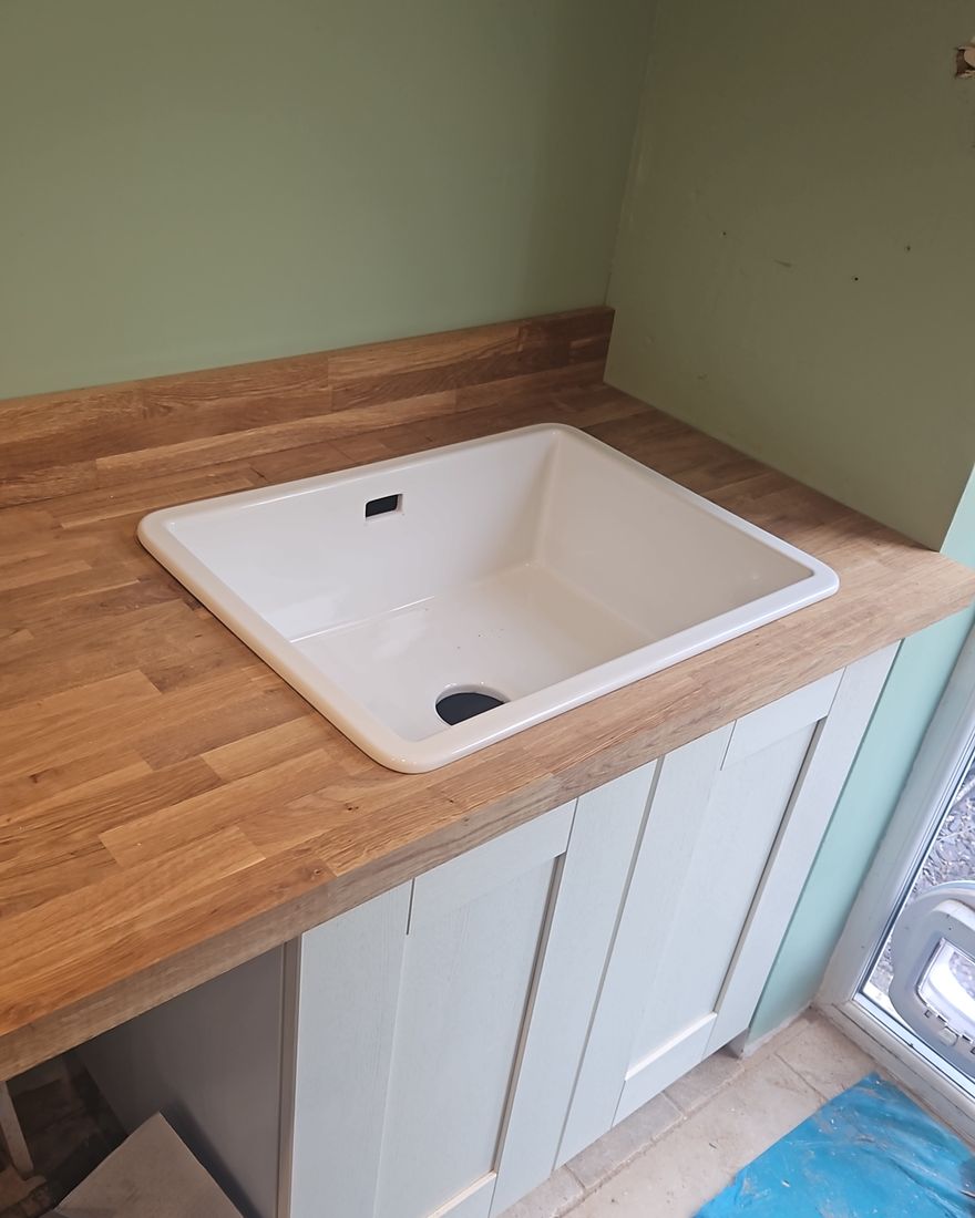 A white Belfast sink set into an oak worktop above a cream shaker unit