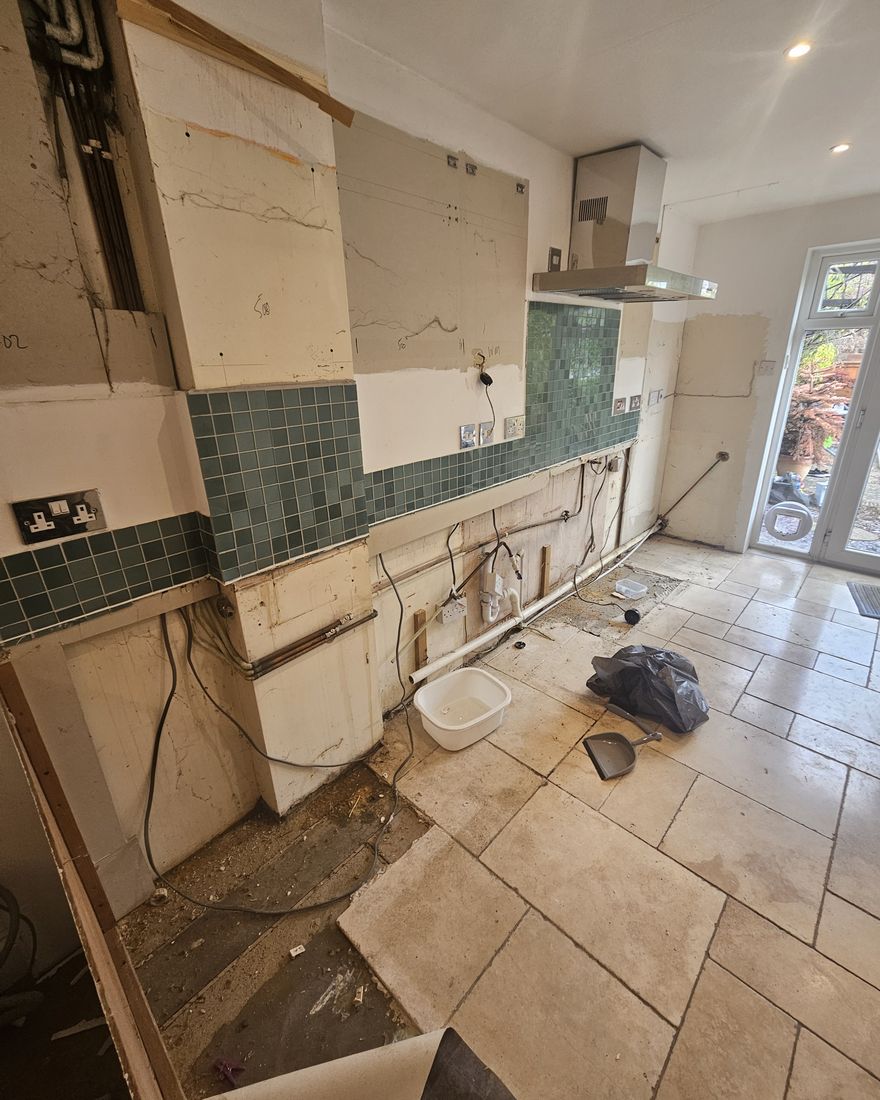 The galley kitchen with the old units removed and the tiled splashback and services exposed