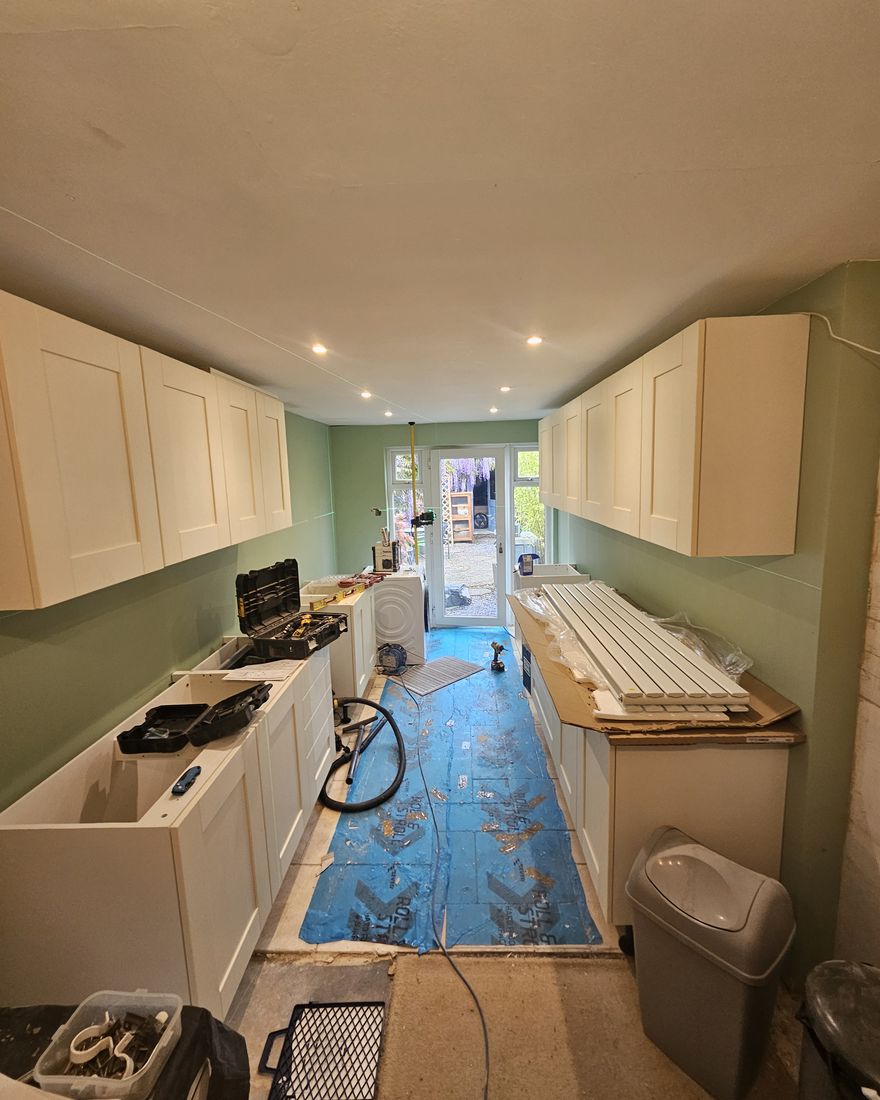 Cream shaker-style units being fitted along both sides of the green galley kitchen
