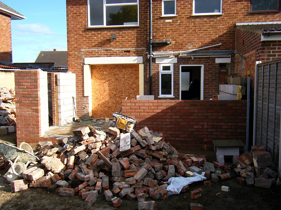 New extension walls going up on the slab, with reclaimed bricks stacked