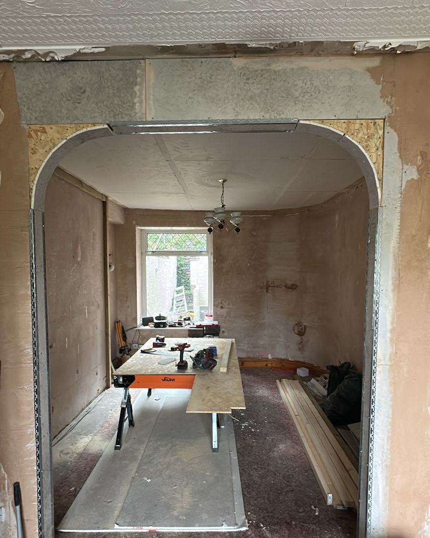 New arched opening between two rooms, with a stripped room beyond