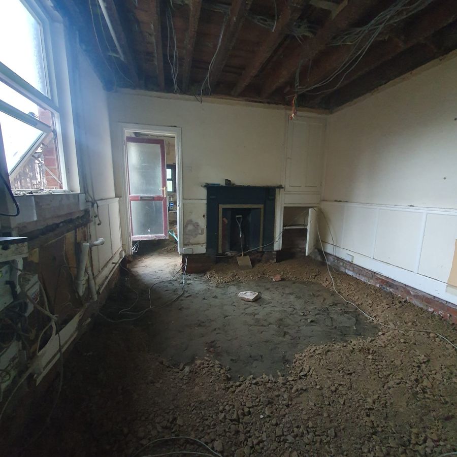 The same room with the ceiling down to the joists and the floor dug out, fireplace at the far end
