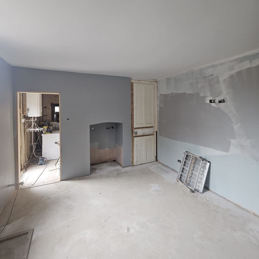 New ceiling, plastered walls and a screeded floor, with the fireplace recess and a doorway