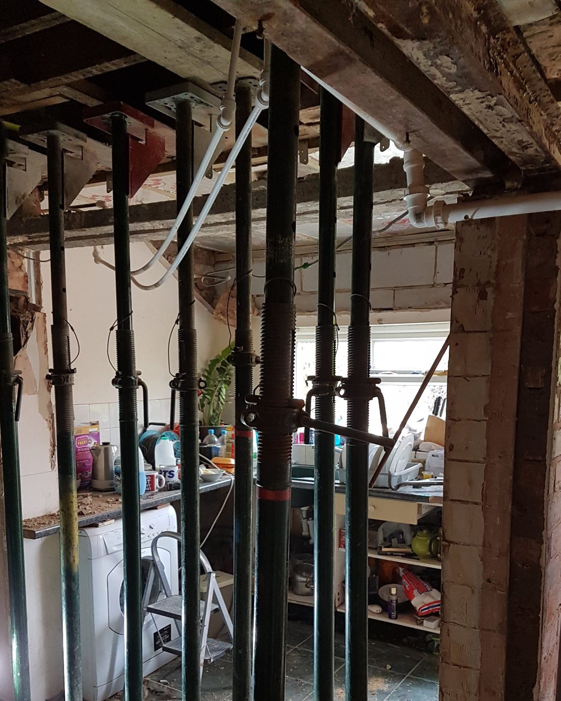 Load-bearing wall removed inside a house, with the floor above supported on a row of Acrow props