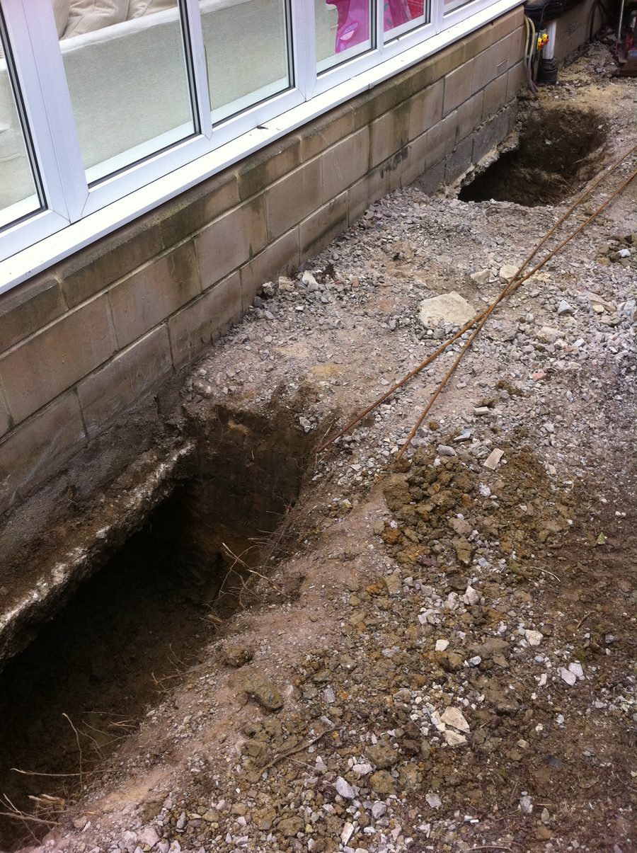Excavations dug alongside the brick base of a conservatory